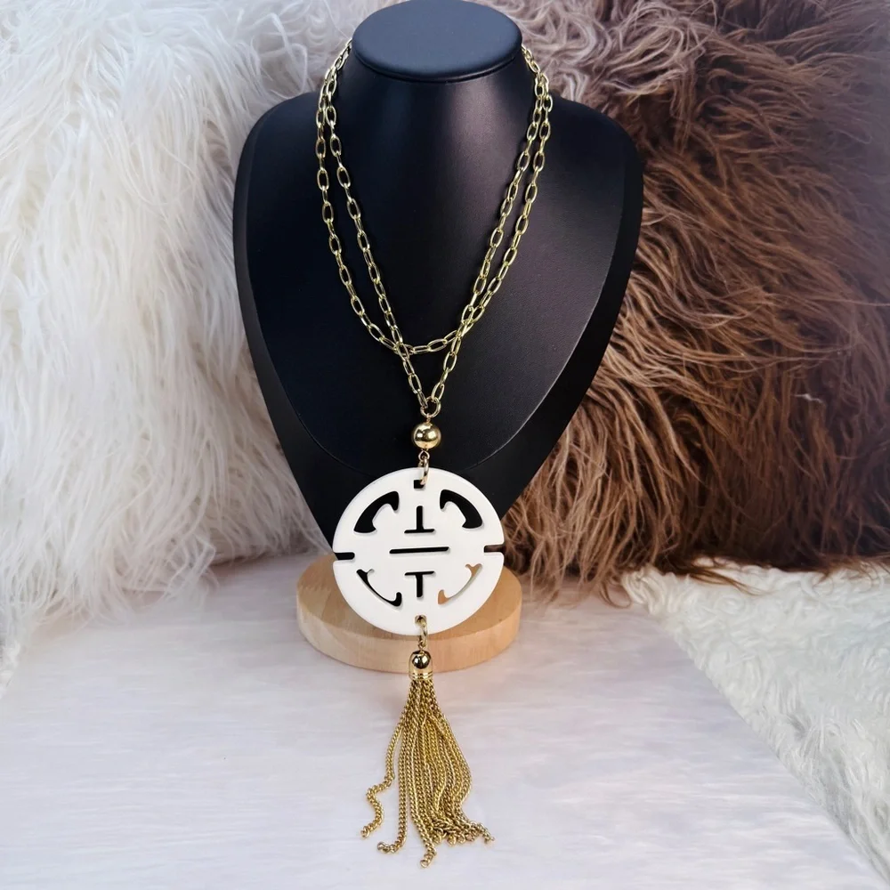 Long, goldtone, costume necklace, with large white pendant, and metal fringe